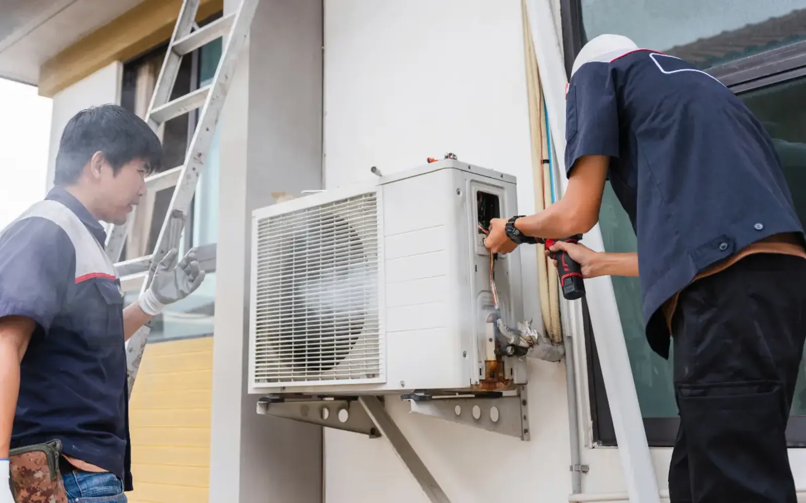 Technicians inspecting an outdoor air-conditioning unit at a Dubai building