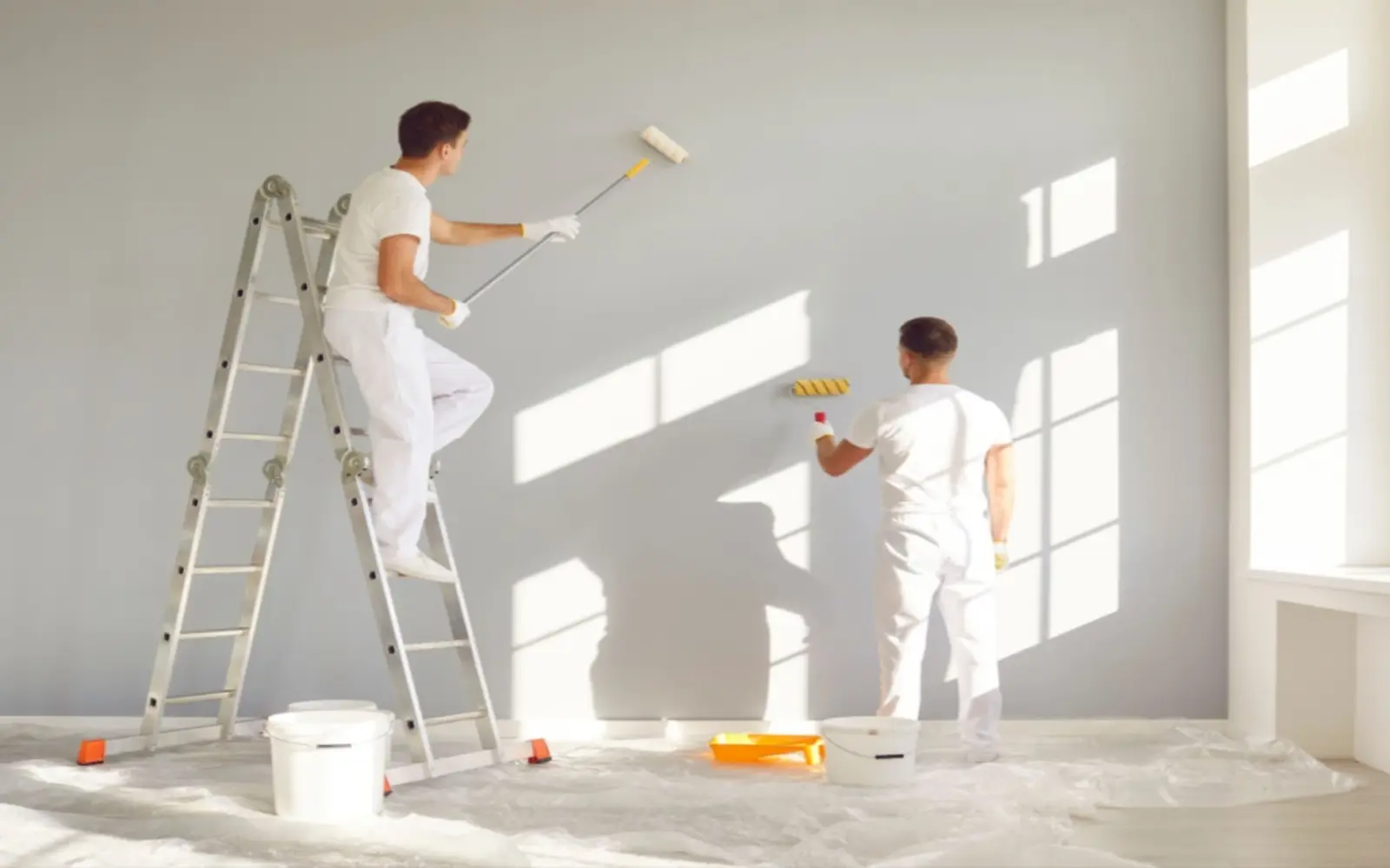 Professional painters applying a clean white wall finish in a bright Dubai interior