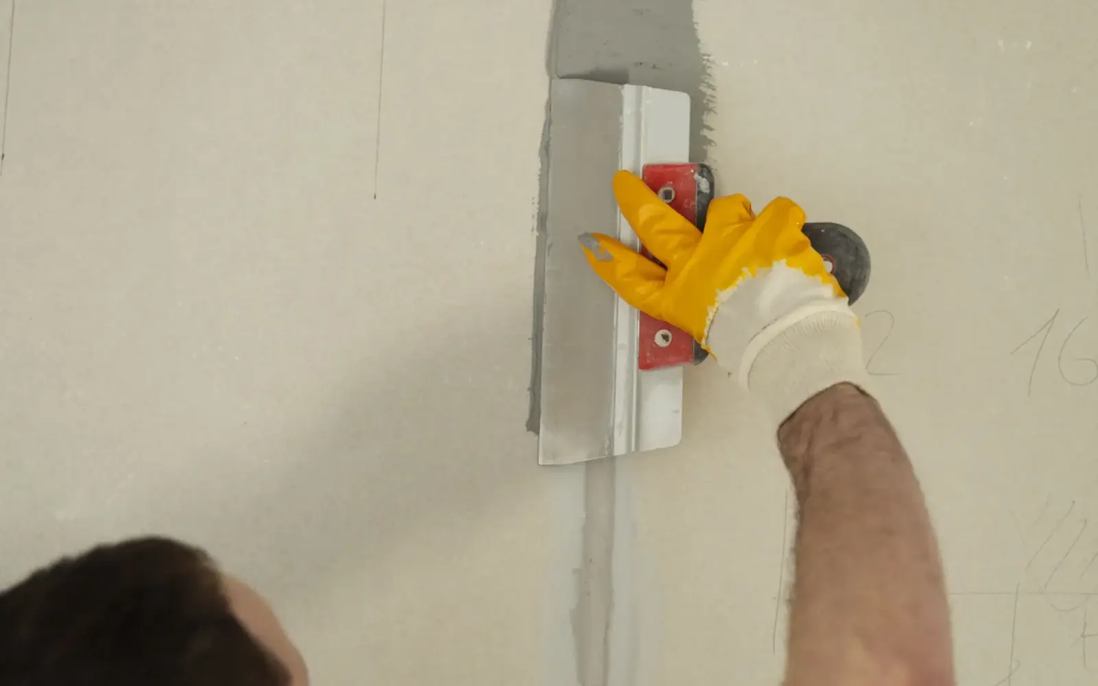 Worker applying plaster repair to a clean interior wall surface
