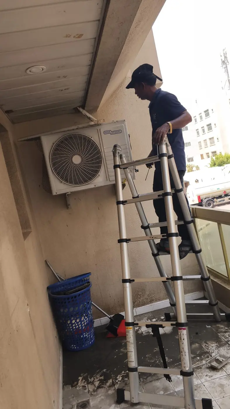 Technician maintaining an outdoor AC unit at a Dubai residence