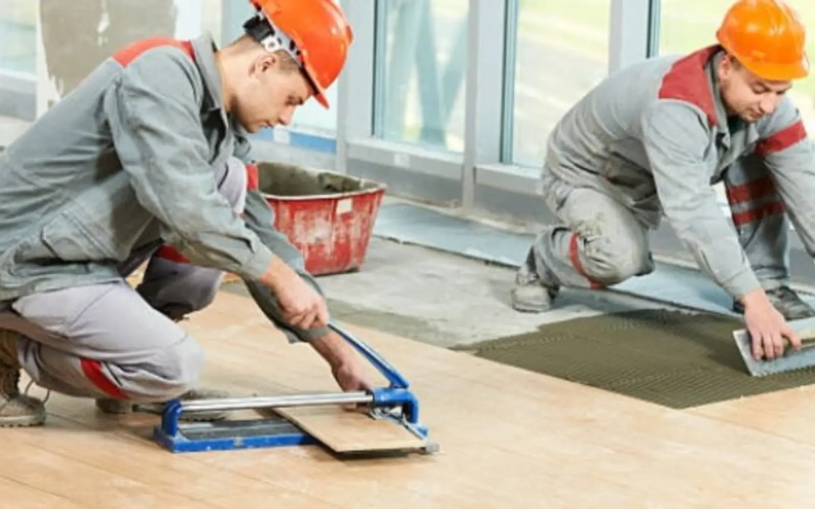 Tilers aligning floor tiles with professional installation tools
